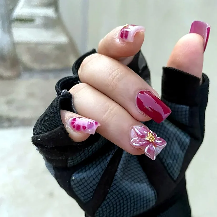 Wine-colored nails with a pink 3D flower and gold details